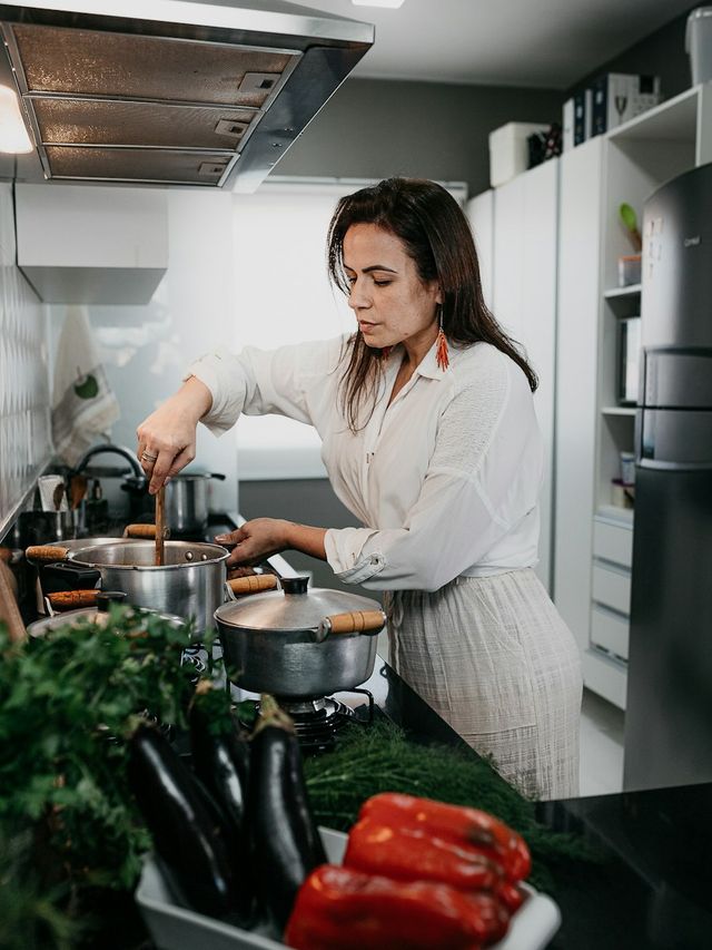 Een vrouw kookt het avondeten op het fornuis